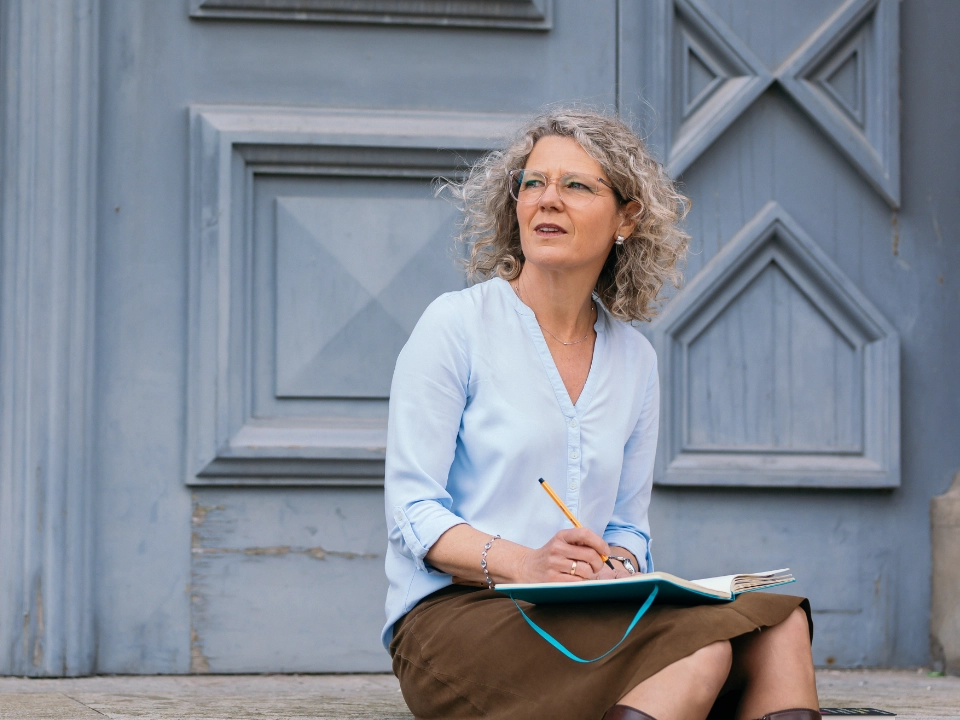 Antje Gorgas sitzt mit einem Notizbuch auf den knien und schreibt